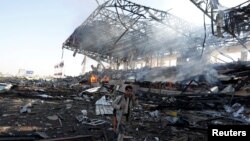 A Houthi fighter talks on the phone as he walks at the site of an airstrike on a parade square in Sana'a, Yemen, Nov. 5, 2017. 