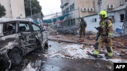 نیروهای پلیس و امدادی اسرائيل در محل اصابت یک راکت شلیک شده از غزه و در کنار خودرویی آسیب دیده - ۱۷ مهر ۱۴۰۲