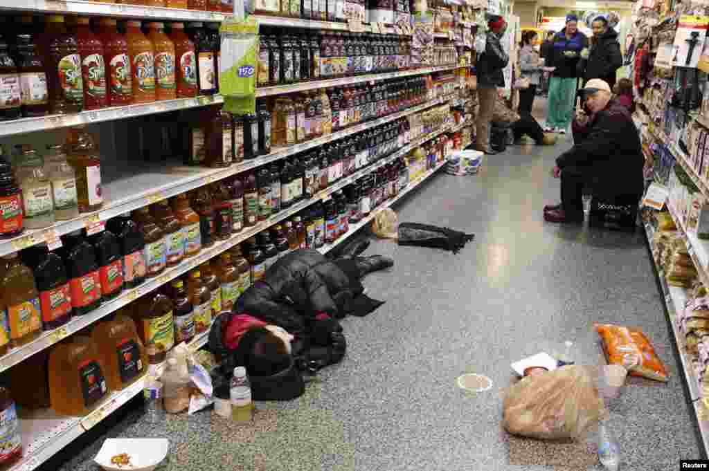 People rest in the aisle of a Publix grocery store after being stranded due to a snow storm in Atlanta, Georgia.