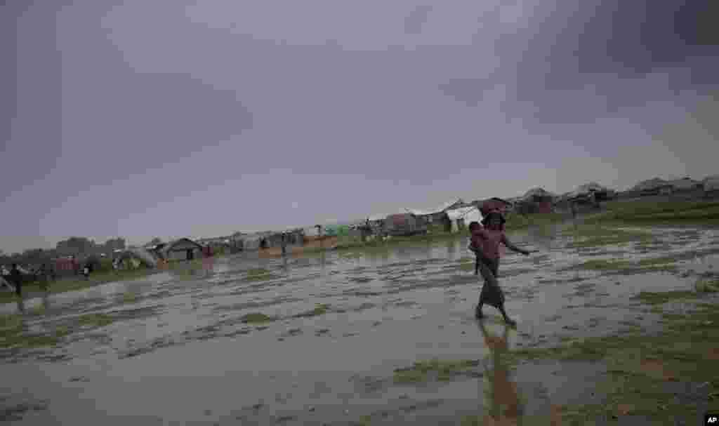 Seorang pengungsi dari kelompok etnis Rohingya menggendong saudaranya di kamp pengungsi darurat di Sittwe, negara bagian Rakhine di barat laut Burma (14/5). PBB mengatakan topan dapat membanjiri kamp yang menampung puluhan ribu anggota kelompok Rohingya. (AP/Gemunu Amarasinghe)