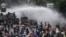 Police officers spray water using a canon to disperse demonstrators during a protest against the government's labour reforms in a polarizing jobs creation bill in Jakarta, Oct. 8, 2020.