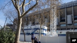 A man is pushed in the wheelchair while wearing protective masks near Real Madrid's Santiago Bernabeu stadium in Madrid, Spain, March 13, 2020.