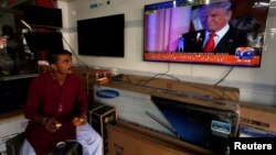Seorang pedagang di Karachi, Pakistan, makan pagi sambil menonton berita soal Donald Trump. (Foto: Dok)