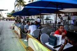 FILE - People eat in an outdoor dining area of a restaurant in Miami Beach, Florida, June 24, 2020.