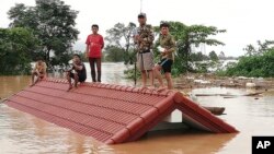 Villagers take refuge on a rooftop above flood waters from a collapsed dam in the Attapeu district of southeastern Laos, July 24, 2018. 