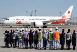 Staff members of Japan Airlines and All Nippon Airways and runway crew wave as they see off the 'Tokyo 2020 Go' aircraft, before it departs for Greece, at Haneda international airport in Tokyo, Japan, March 18, 2020.