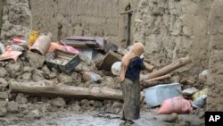 زنی در برابر خرابه‌های منزلش در منطقه کوشی در استان لوگار، افغانستان