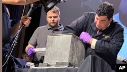 Paul Hudson, left, and Michael Diaz take part in the opening of a lead box believed to have been placed in the base of a monument almost two centuries ago, at the U.S. Military Academy, on Aug. 28, 2023, in West Point, N.Y. (AP Photo/Michael Hill)