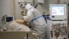 A medical staff member wearing a special suit to protect against COVID-19 treats a patient with coronavirus at an ICU at the Regional Clinical Hospital 1, in Krasnodar, southern Russia, Nov. 2, 2021.