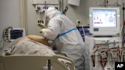 A medical staff member wearing a special suit to protect against COVID-19 treats a patient with coronavirus at an ICU at the Regional Clinical Hospital 1, in Krasnodar, southern Russia, Nov. 2, 2021.