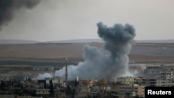 Asap membubung di Kobani, Suriah, terlihat dari perbatasan Turki-Suriah, Suruc (9/10).