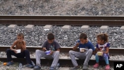 FILE - Migrant children eat sitting on railroad tracks as they wait to board a northbound freight train, in Huehuetoca, Mexico, May 12, 2023.