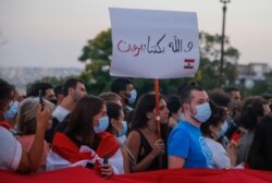 A member of the Lebanese community holds a placard that reads "For Beirut we cry," during a vigil in front of Sacre Coeur Basilica in memory of victims of the deadly blast in Beirut, in Paris, France, Aug. 5, 2020.