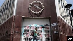 FILE - A woman walks in front of a closed bank in the neighborhood of Rio Piedras in San Juan, Puerto Rico, June 29, 2015. 