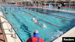 People swim at a pool where a 'Green Badge' is required to enter, as Israel reopens swathes of its economy, continuing to lift restrictions of a national lockdown to fight COVID-19, at Gordon Gym and Pool in Tel Aviv, Feb. 21, 2021.