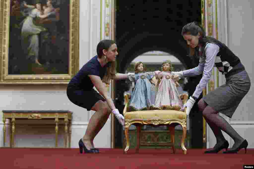 Exhibition curator Anna Reynolds (L) poses with a pair of Parisian dolls belonging to Britain&#39;s Queen Elizabeth (left doll) and her sister Princess Margaret, at Buckingham Palace in London. Toys and childhood outfits belonging to the royal family will form part of an exhibition &quot;Royal Childhood&quot; during the summer opening of Buckingham Palace from Jul. 26 - Sept. 28, 2014.