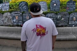 A man looks at cardboard gravestones with the names of victims of opioid abuse outside the courthouse where the Purdue Pharma bankruptcy is taking place in White Plains, NY, Aug. 9, 2021.