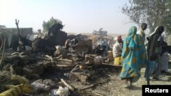 People return to the site after a bombing attack by a Nigerian military jet of an internally displaced persons camp in Rann, Nigeria Jan. 17, 2017. Officials say the bombing was an accident and is under investigation.