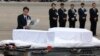 Japanese Foreign Minister Fumio Kishida, left, lays flowers on the coffins of the victims who were killed in the last weekend's attack on a restaurant in Bangladeshi capital Dhaka, at Haneda Airport in Tokyo, Tuesday, July 5, 2016.