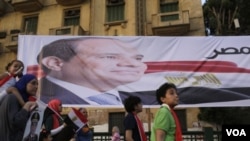 Warga Mesir berjalan melewati poster mantan pemimpin militer Abdel Fattah al-Sisi di Lapangan Tahrir dan merayakan kemenangannya dalam Pemilu Presiden di Kairo (3/6).