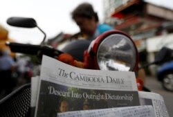 FILE - A woman buys the final issue of The Cambodia Daily newspaper at a store along a street in Phnom Penh, Cambodia, Sept. 4, 2017.