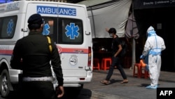 បុគ្គលិកសុខាភិបាលម្នាក់ស្ថិតក្នុង​សម្លៀកបំពាក់ការពារពីការឆ្លងជំងឺកូវីដ១៩ ត្រៀមបញ្ជូនបុរសម្នាក់ដែលមានតេស្តវិជ្ជមានជំងឺកូវីដ១៩ ទៅកាន់មណ្ឌលព្យាបាលអ្នកជំងឺ នៅរាជធានីភ្នំពេញ កាលពីថ្ងៃទី១៩ ខែមីនា ឆ្នាំ២០២១។