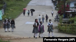 Wearing masks to curb the spread of the new coronavirus, students walk to the one open school in Campohermoso, Colombia, Thursday, March 18, 2021. (AP Photo/Fernando Vergara)