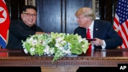 도널드 트럼프 미국 대통령과 김정은 북한 국무위원장이 지난 2018년 6월 싱가포르에서 열린 첫 정상회담에서 합의문에 서명한 후 악수하고 있다.
