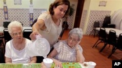 Cristina Couto, supervisor at Ironbound Senior Center, pours water for elderly bingo players, Newark, New Jersey, June 21, 2012.
