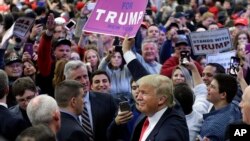 Republican presidential candidate Donald Trump holds up a sign handed to him by a supporter after speaking at a campaign rally in Bethpage, New York, April 6, 2016. 