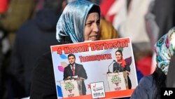 FILE - A protestor shows pictures of detained Turkish HDP politicians Selahattin Demirtas and Figen Yuksekdag at a demonstration against Turkish president Recep Tayyip Erdogan and political repression that followed July's failed military coup, Cologne, Germany, Nov. 12, 2016. 