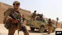 FILE - Afghan National Army commandos take position during a military operation in Helmand province, Oct. 2, 2016.