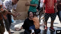 A woman reacts as a girl hugs her during minor clashes between riot police and migrants near Mytilene town, on the northeastern island of Lesbos, Greece, Sept. 12, 2020.