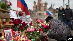 A woman lights a candle at the location where Russian opposition politician Boris Nemtsov was assassinated on February 27, 2015, near the Kremlin, in Moscow on April 7, 2015.