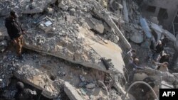 গাজা সিটির দক্ষিণে ইসরায়েলি হামলার পর একটি ভবনের ধ্বংসাবশেষ দেখছে ফিলিস্তিনিরা। ফটোঃ ২২ নভেম্বর, ২০২৪।