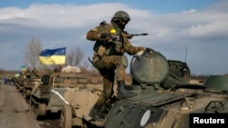 Konvoi pasukan bersenjata Ukraina menarik mundur kendaraan lapis baja, meriam dan senjata lainnya, dari kota Blagodatne, di wilayah Debaltseve, Ukraina Timur (27/2).