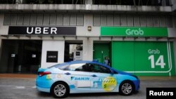 Sebuah taksi ComfortDelgro melintas di depan kantor Uber dan Grab di Singapura, 26 Maret 2018. 