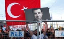 FILE - A supporter of Turkey's main pro-Kurdish Peoples' Democratic Party (HDP) holds a portrait of its jailed former leader and presidential candidate Selahattin Demirtas during a campaign event in Istanbul, Turkey, June 17, 2018.