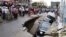 ​​Onlookers watch the cars sink in a hole by a construction site by Phnom Penh's Olympic Stadium after a heavy rain on Wednesday, June 8, 2016. (Courtesy of SBN)