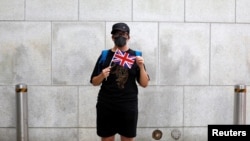 一名香港抗议者在英国驻港总领事馆外手举英国国旗。（2019年8月21日）