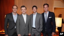 An Indian laborer talks on his mobile phone as he transports a refrigerator on his back at a market in Jammu.