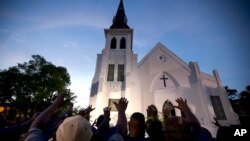 FILE - Members of the Omega Psi Phi Fraternity lead a crowd of people in prayer outside the Emanuel African Methodist Episcopal Church after a memorial for the nine people who were shot and killed during Bible study in Charleston, S.C., June 19, 2015.
