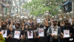Anti-coup protesters holding pictures of those who died during a protest against the military offer prayers for them, in Yangon, Myanmar, Monday, April 5, 2021. 