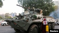 Seorang biksu Buddha memegang tanda berdiri di samping kendaraan lapis baja selama protes terhadap kudeta militer, di Yangon, Myanmar, 14 Februari 2021. (Foto: Reuters)