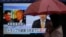 FILE - A woman walks past a public TV screen showing North Korean leader Kim Jong Un, left, and U.S. President Donald Trump, right, in Tokyo, March 9, 2018. The signs reads: "Trump has accepted an offer of a summit from the North Korean leader and will meet with Kim by May."