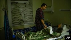 FILE - Dr. Ivan Mozhaiev attends to a patient during morning rounds at Pokrovsk hospital in Pokrovsk, Ukraine, on May 22, 2022. The country's health system is bracing for a second winter of war.