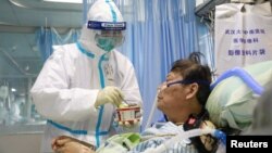 A nurse in a protective suit feeds a novel coronavirus patient inside an isolated ward at Zhongnan Hospital of Wuhan University, during the Lantern Festival, which marks the end of the Chinese Lunar New Year celebrations, in Wuhan, Hubei province.
