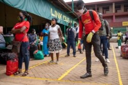People queue to buy bus tickets while adhering to social distancing measures and wearing masks to curb the spread of the coronavirus at the Namirembe Bus Park in Kampala, Uganda, June 4, 2020.