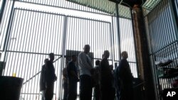 FILE - Persons are detained for being in the country illegally and are moved out of the holding area after being processed at the Tucson Sector of the U.S. Border Patrol's headquarters in Tucson, Arizona, Aug. 9, 2012.