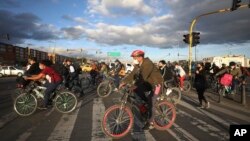 Commuters ride their bicycles, most of them to their jobs, in Bogota, Colombia, Friday, Aug. 28, 2020. The city has mandated that public parking lots expand spaces for bicycles by 20% and refurbished paths that run along busy roads next to cars. (AP Photo
